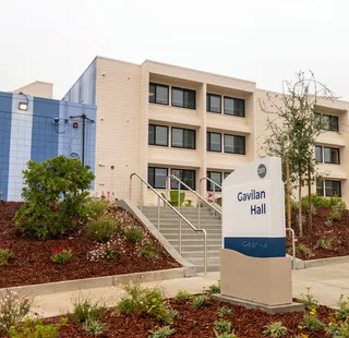 Exterior of Gavilan Hall, a Cal State Monterey Bay residence hall, with landscaping and the building sign in front.