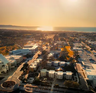 An arial photo of CSUMB as the sunsets over the ocean in the background