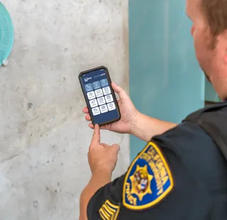 Officer promoting the UDP Safe app on a phone
