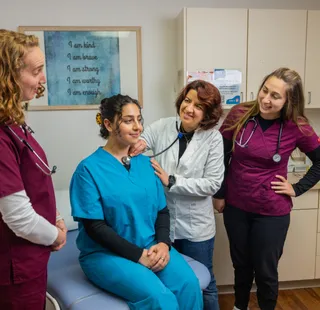A professor giving a presentation to nursing students in scrubs about checking someones pulse
