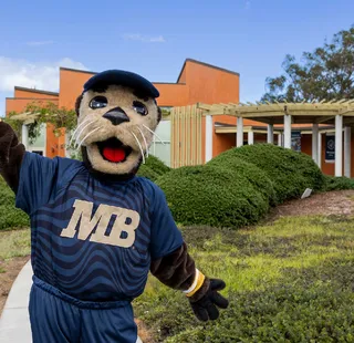 Monte Rey, ���ӽ紫ý mascot, posing in front of the Alumni and Visitor Center Building