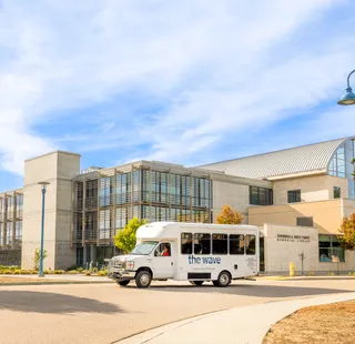 The Wave, CSUMB's student shuttle, parked in front of a campus building.