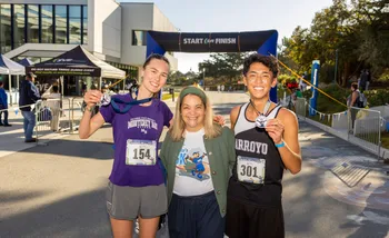 Two runners with medals pose with President Vanya