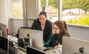 Professor helping a student at her desk in a classroom