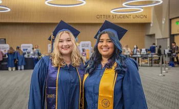 Two students in their cap and gown at grad fest