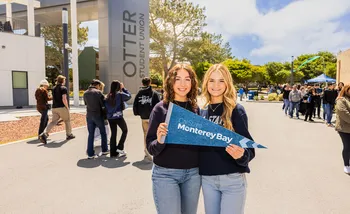 Students hold a Monterey Bay sign on campus, highlighting school spirit and community engagement.