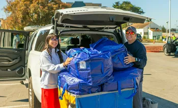 Female Student and supporter with blue totes unloading from trunk