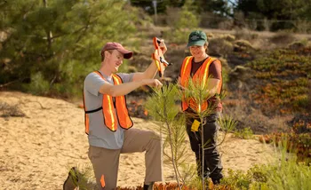 Two AES students survey a tree sapling.