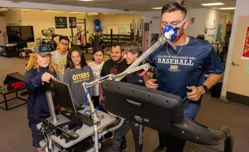 A student on a treadmill with an oxygen mask with other students watching.