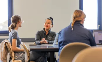 Three people sitting at tables with laptops