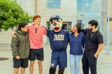 Monte hanging out with a group of students in front of the library