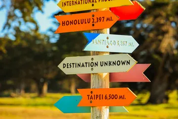 Colorful directional signs point to global destinations, symbolizing exploration and international connection.