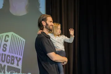 Man is holding a child on a stage