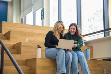 Two students sitting in the OSU looking at a laptop