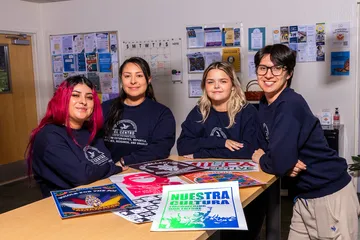 Students at a table of El Centro event posters.