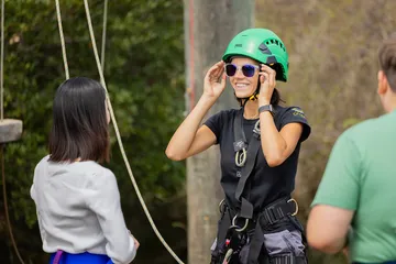 Girl in climbing gear with ropes behind her.