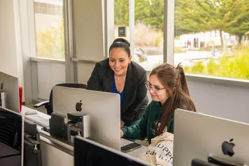 Professor helping a student at her desk in a classroom