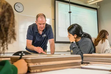 A professor speaking to a student in a classroom