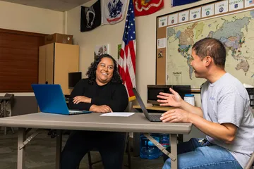 Veteran talking with a student in a classroom.