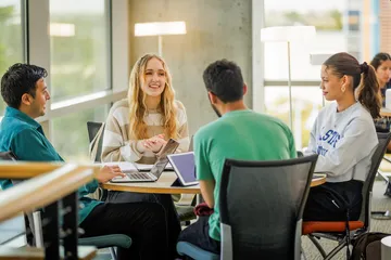 A group of four students sitting around a table and talking