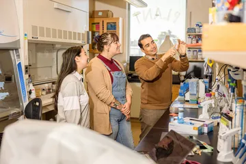 A faculty member guides students through a hands-on lab activity, demonstrating techniques in a collaborative learning environment