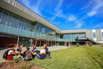 Group of students sitting on grass outside the CAHHS building