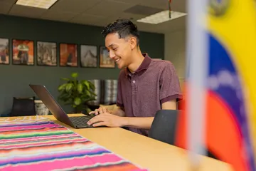 Student typing on a laptop inside El Centro.