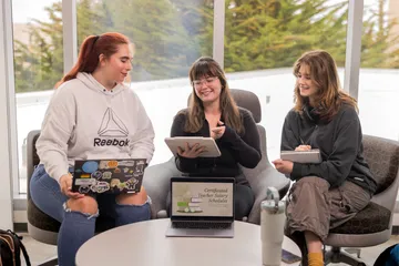Three students doing group work sitting around a table talking