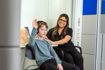 Professor conducting a listening test on a child.