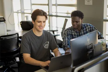 Two students collaborating together in the business and information technology building