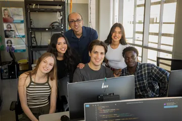 A group of students and a professor in front of a computer in the business and information technology building