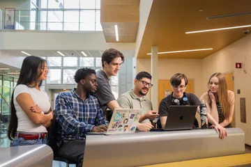 Group of students collaborating on a computer in the Business and Information Science building.