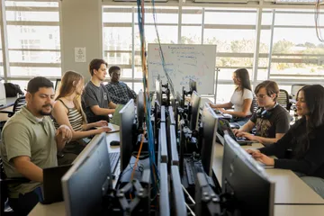 A group of students working on their desktops in the network and security lab in the business and information technology building
