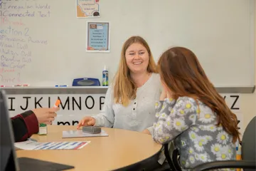 Teacher helping a kid read in the reading center