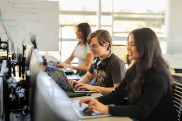 A group of students working on their laptops in the business and information technology building