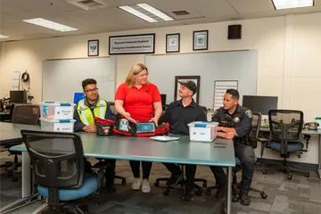 Wide shot of the emergency training session showing the setup of medical bins and instructional material being demonstrated to ���ӽ紫ý personnel