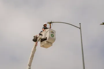A facilities worker repairing a street light in a boom lift