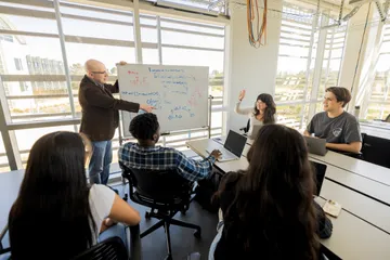 A group of students listening to their professor give a presentation