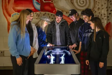 A professor giving a presentation to a group of students using a digital anatomy board