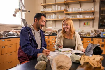 Two AES students in a lab collaborating together while examining a rock