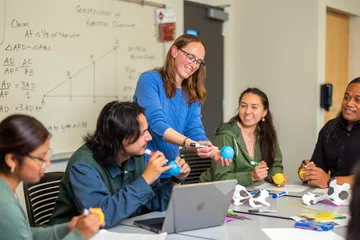 Professor interacting with students while teaching them a math concept.