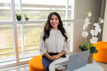 A masters of business administration professor sitting down on a chair smiling at the camera