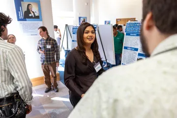 A student presenter presents their presentation to an audience member