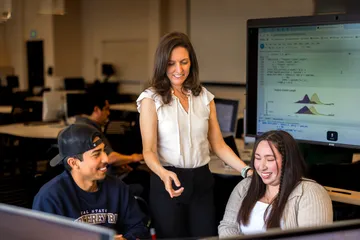 Dr. U assisting two students with statistics in a classroom setting