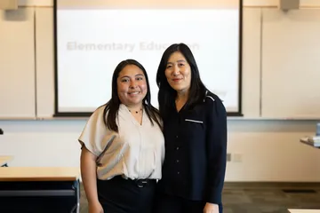 Student and professor smiling next to each other in a classroom for a photo.