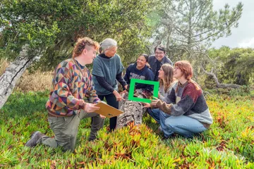CSUMB environmental science students and faculty examine a fallen tree in a coastal habitat during an outdoor field lesson.