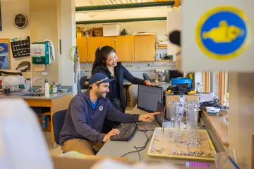 Two people collaborating while working together on a computer in a lab.