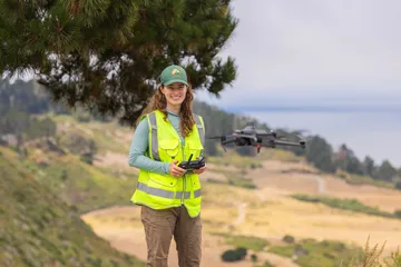 Alumni student doing work outside while holding a drone.