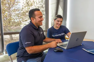 Two students sitting together looking at a laptop
