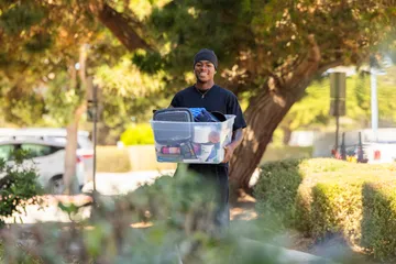 Student moving in, carrying a box of belongings